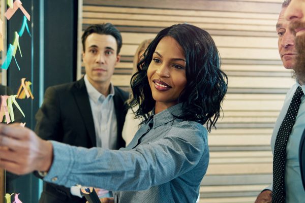 Creative group of business people brainstorming putting sticky notes on glass wall in office